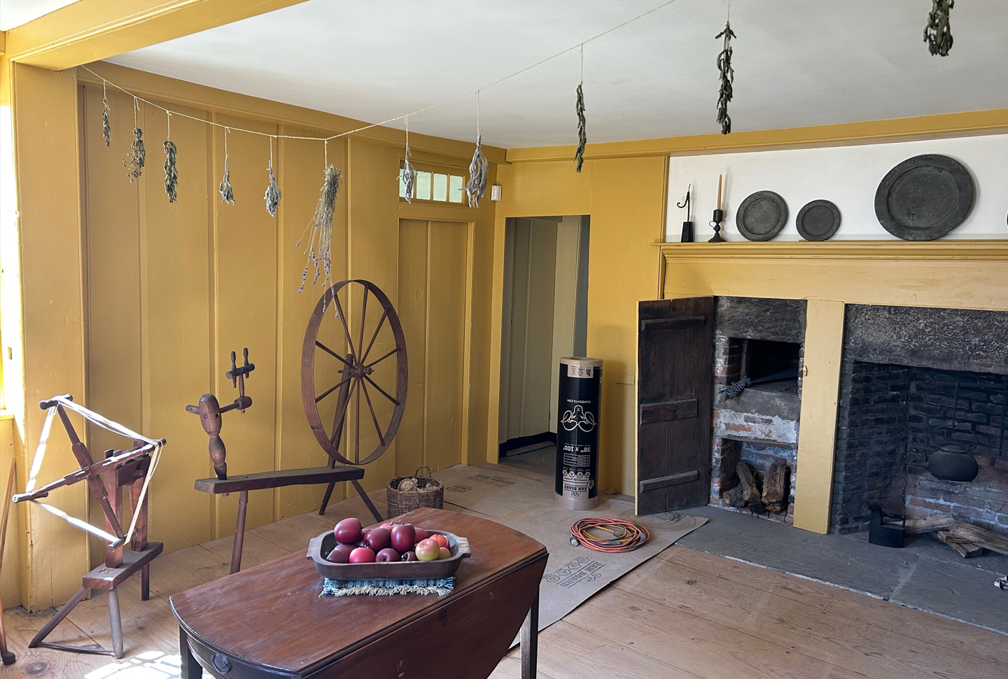 The keeping room, or kitchen, where women and servants prepared food and drink, dried and hung herbs, and spun thread.